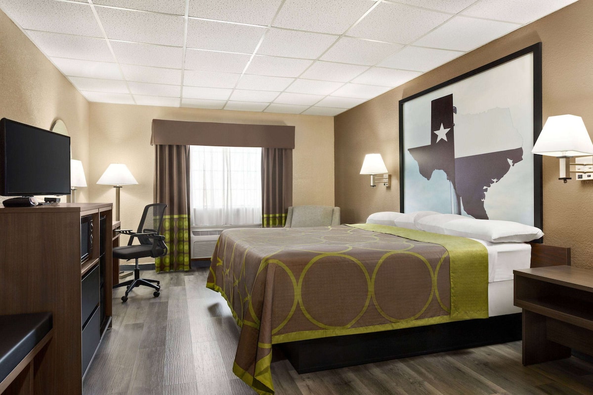 Ein Hotelzimmer mit Bett, Schreibtisch, Stuhl, Fernseher und einer großen Wandkarte.