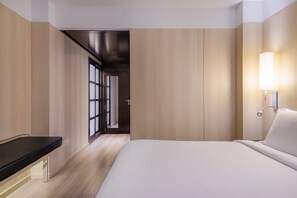 A modern hotel room with a bed, bedside table, and a wall-mounted lamp. - AC Hotel Córdoba by Marriott (Córdoba)