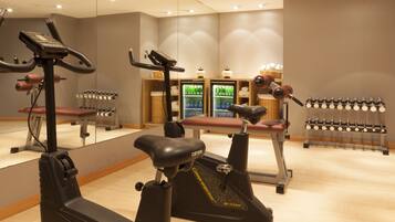 A gym with stationary bikes, treadmills, and a wall-mounted dumbbell rack.