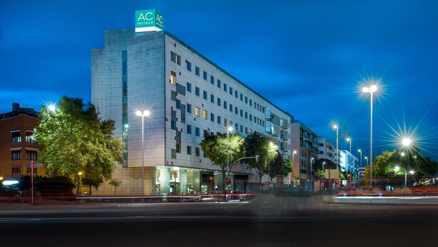 A multi-story hotel with a modern facade, illuminated signage, and street-level lighting. - AC Hotel Córdoba by Marriott (Córdoba)