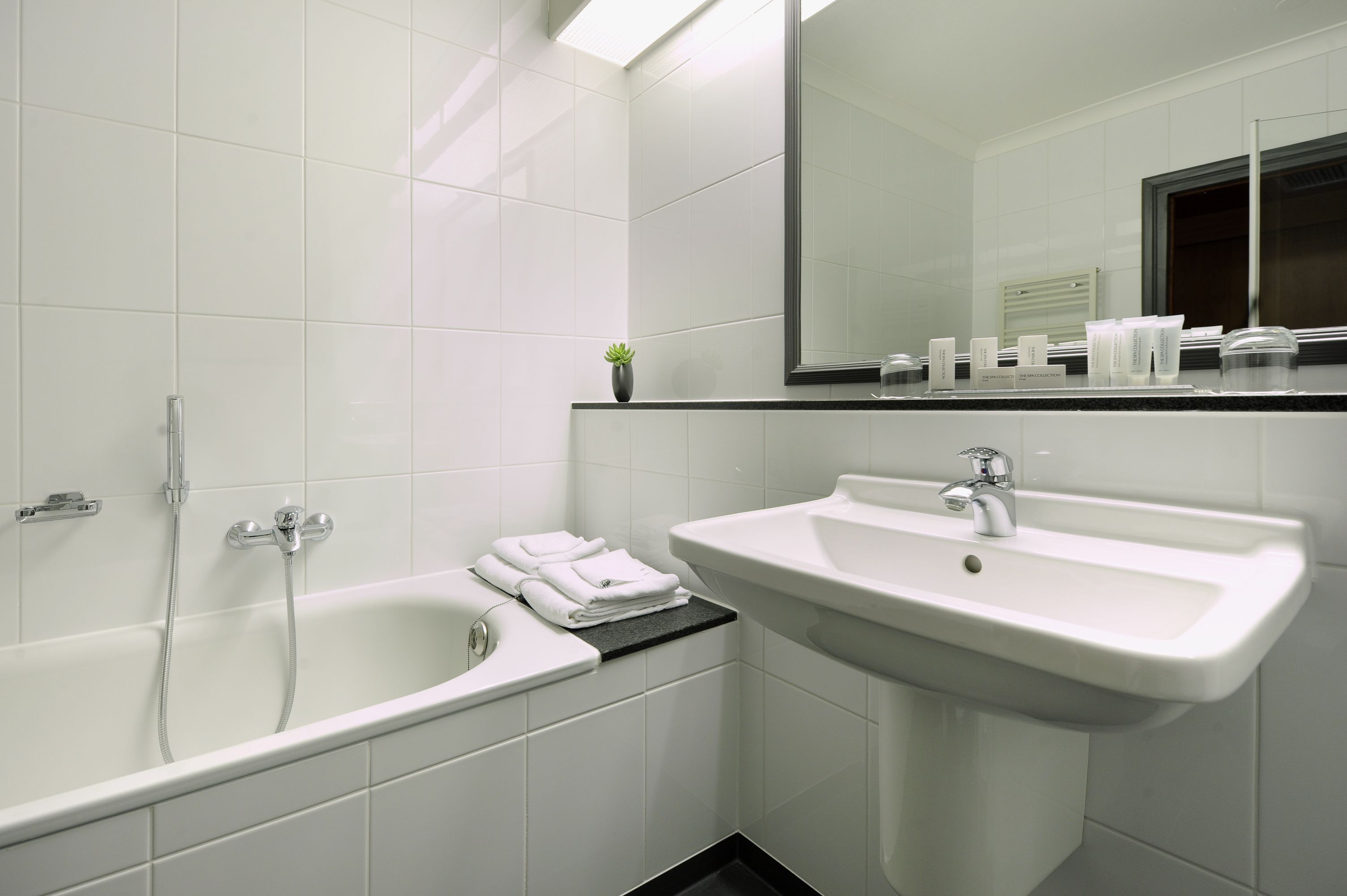 Un baño moderno con bañera, lavamanos y espejo.