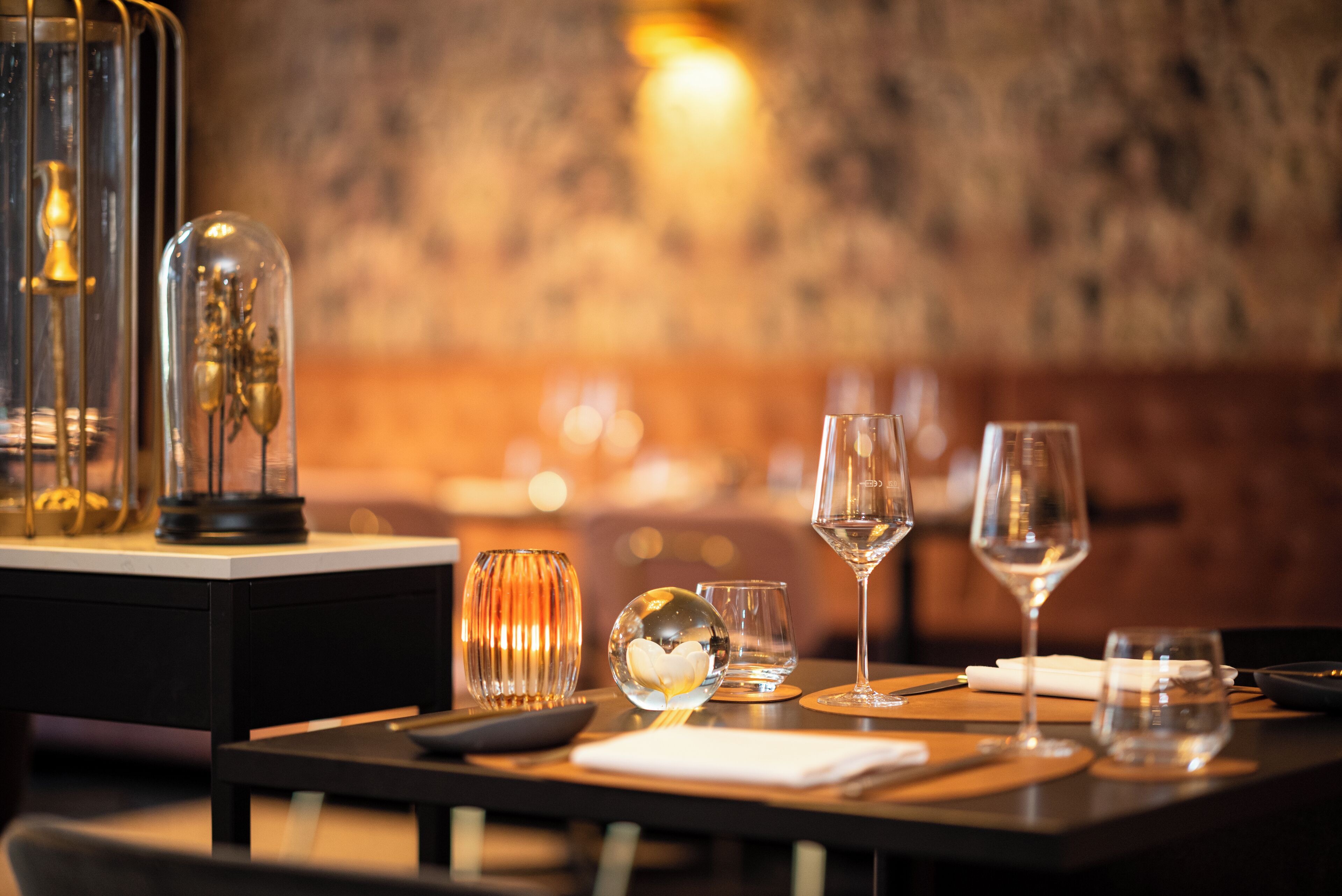 A dining table set with wine glasses, a clear glass bowl, and a candle holder.