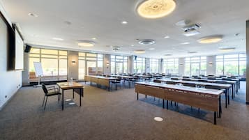 Una sala conferenze con lunghe tavolate e sedie, ampie finestre e luci a soffitto.