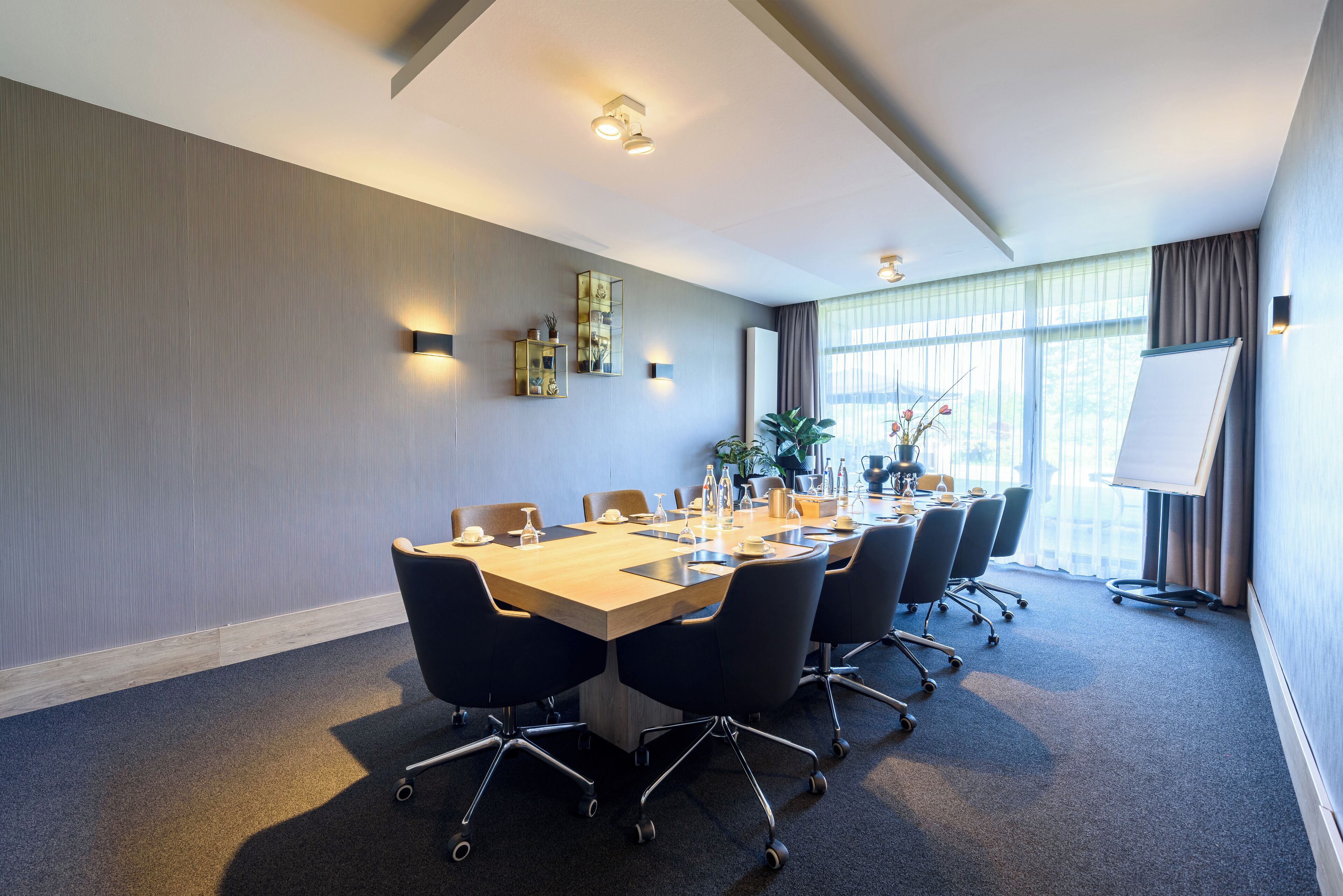 A conference room with a long table, chairs, a whiteboard, and a large window with curtains.