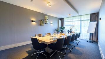 A conference room with a long table, chairs, a whiteboard, and a large window with curtains.