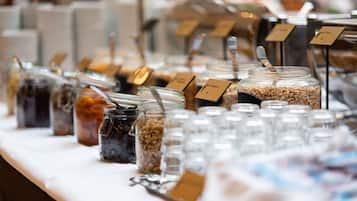 Una mesa de buffet con diversos alimentos en frascos y recipientes, cada uno con una tarjeta identificadora.