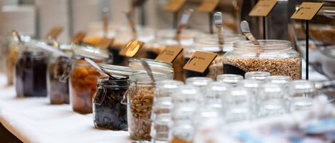 A buffet table with various food items in jars and containers, each labeled with a card.