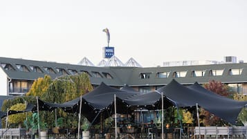 Un hotel con terraza en la azotea, zona de estar al aire libre e identificación del nombre del hotel con una bandera.