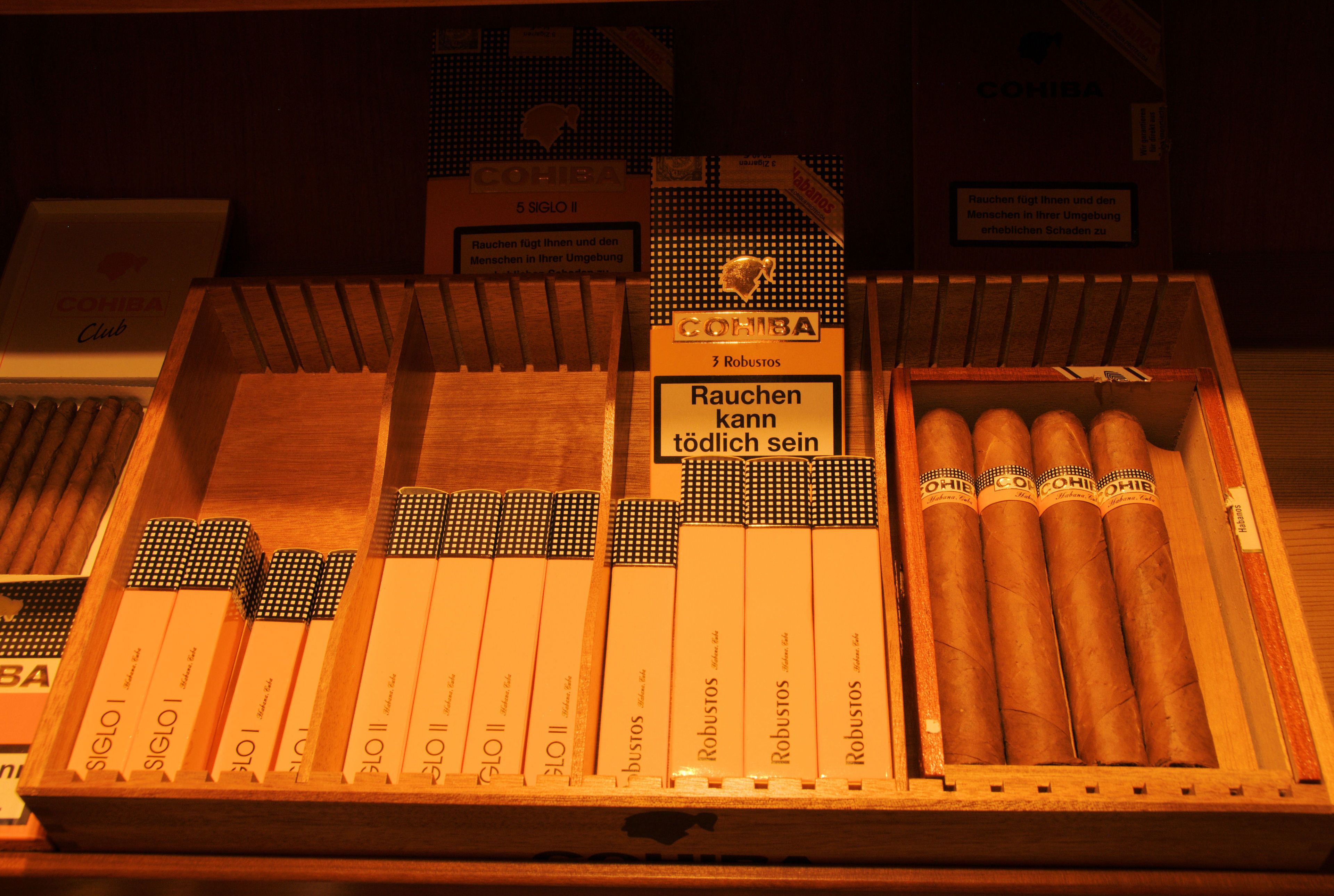 Une boîte en bois contenant divers types et marques de cigares, notamment les modèles « Siglo II » et « Robustos ».