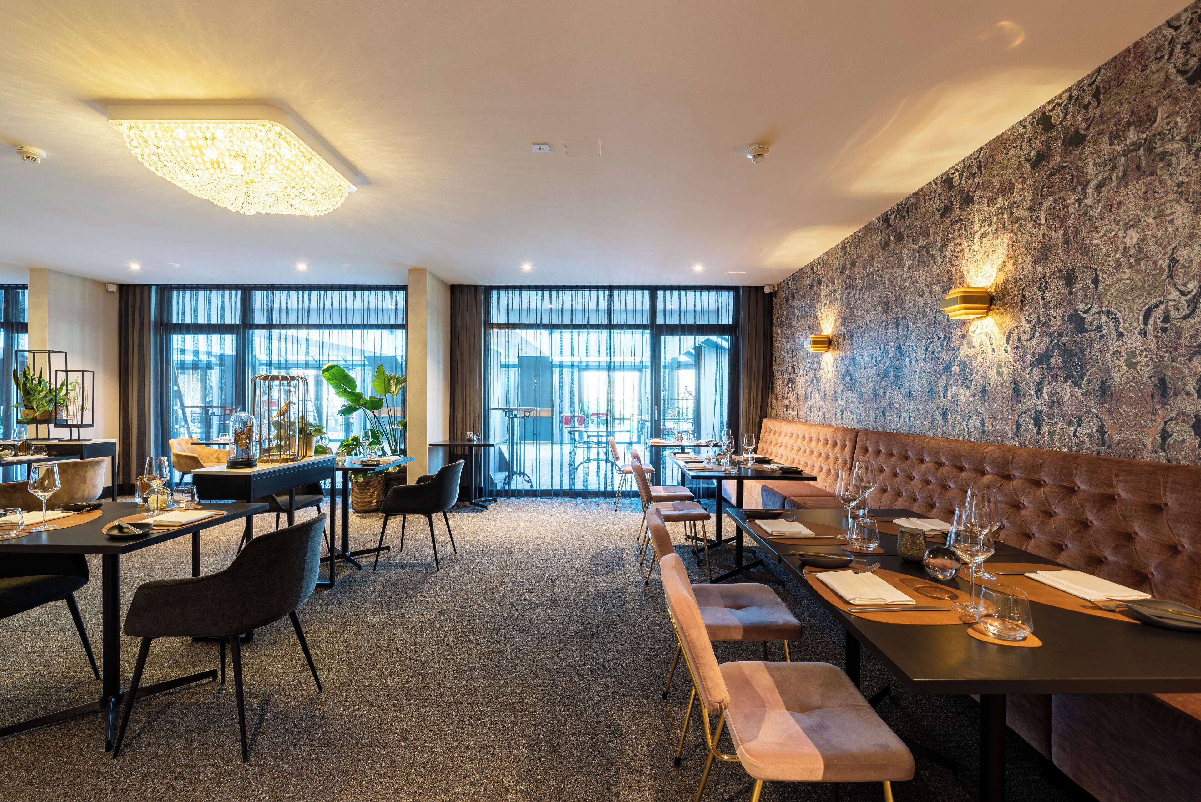 A modern dining area with tables and chairs, a large window with a view, and decorative wall sconces.