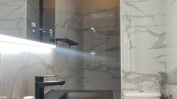 A bathroom with a marble wall, a black sink, and a toilet.