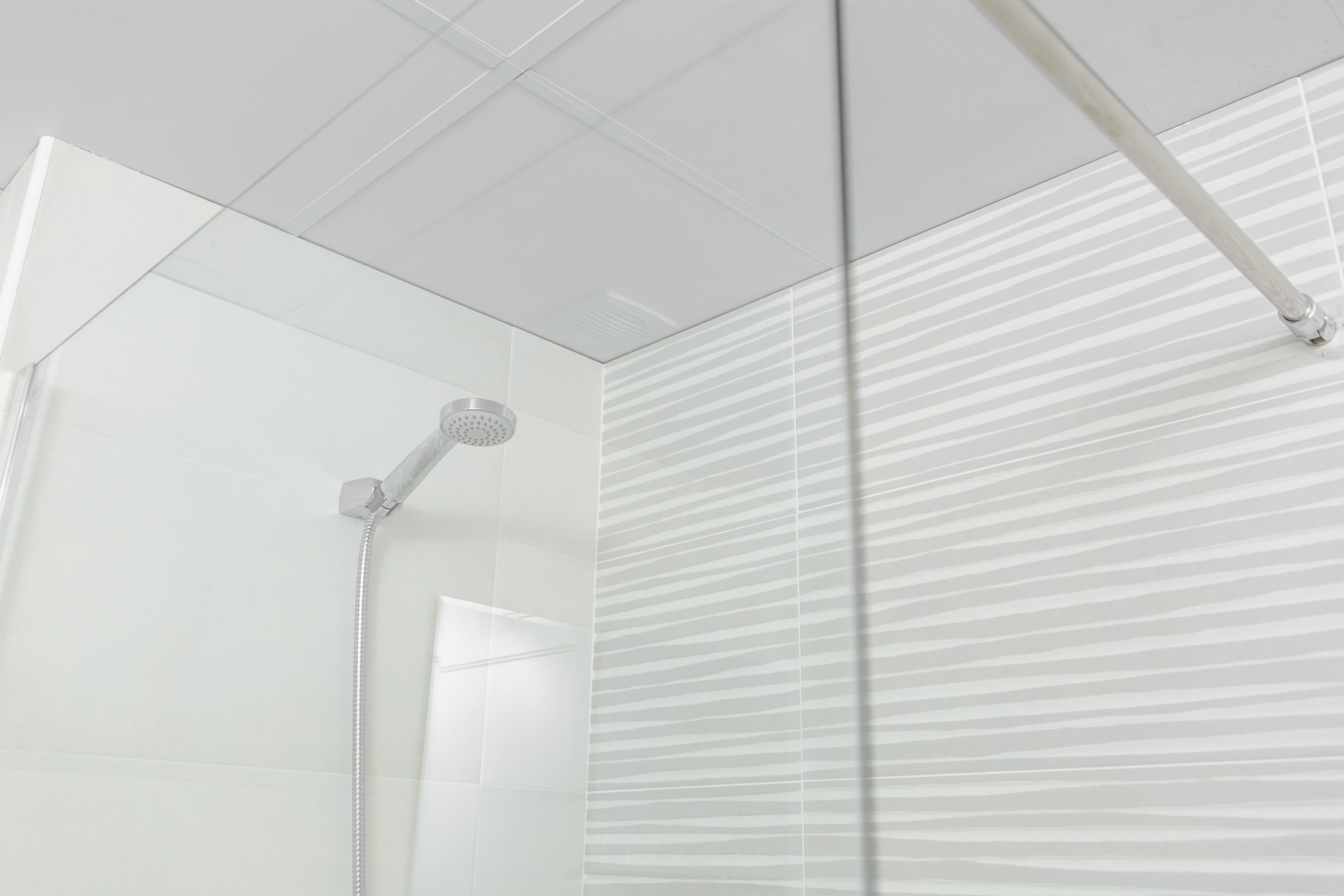 A modern bathroom with a glass shower enclosure, a visible showerhead, and a striped wall pattern.