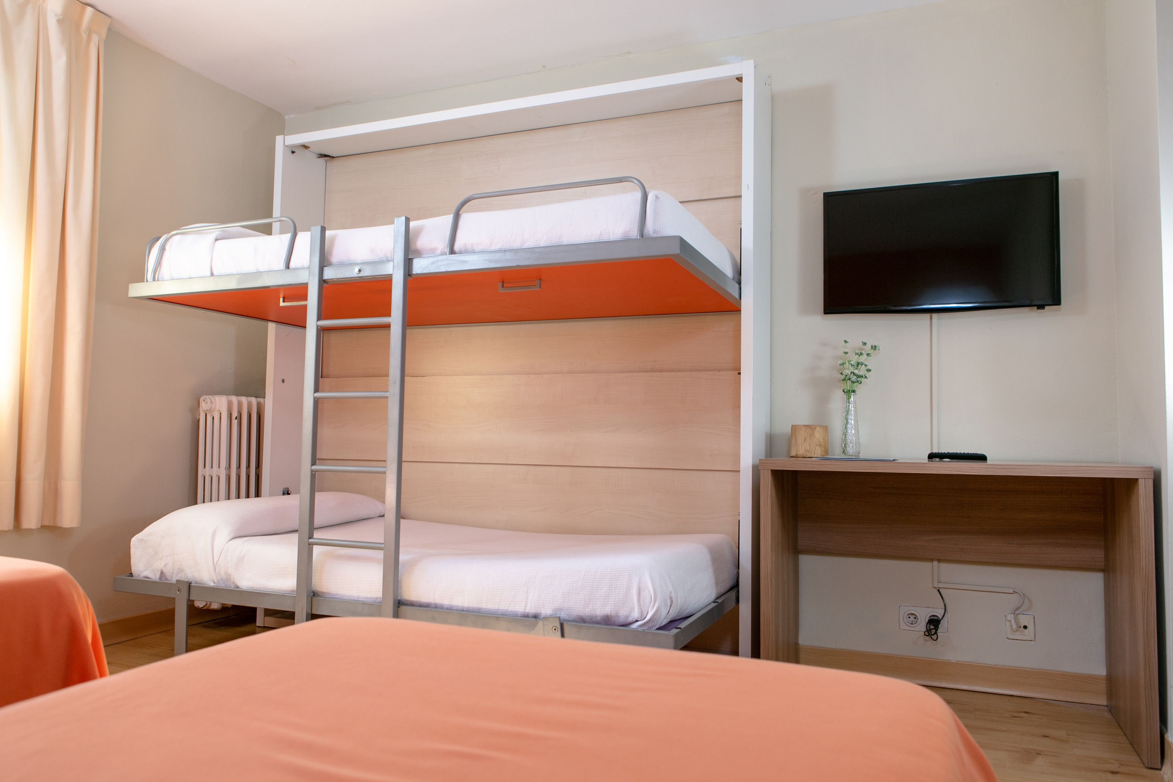 Camera con letto a castello, televisore e un piccolo tavolo.
