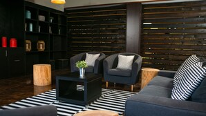 Un salon moderne avec un canapé foncé, deux fauteuils, une table basse et un tapis rayé noir et blanc.