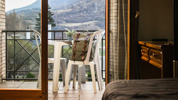 Un balcon avec une table et des chaises, un pot de fleurs et une vue sur les montagnes.