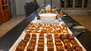 Une table de buffet garnie de divers desserts et un grand saladier blanc placé au centre.