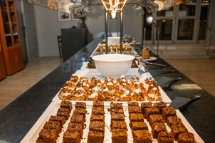 Una mesa de buffet con diversos postres y un recipiente blanco grande en el centro.