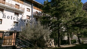 Un hôtel à la façade blanche, doté de balcons et d’un escalier menant à l’entrée.