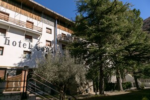 Un hotel con fachada blanca, balcones y una escalera que lleva a la entrada.