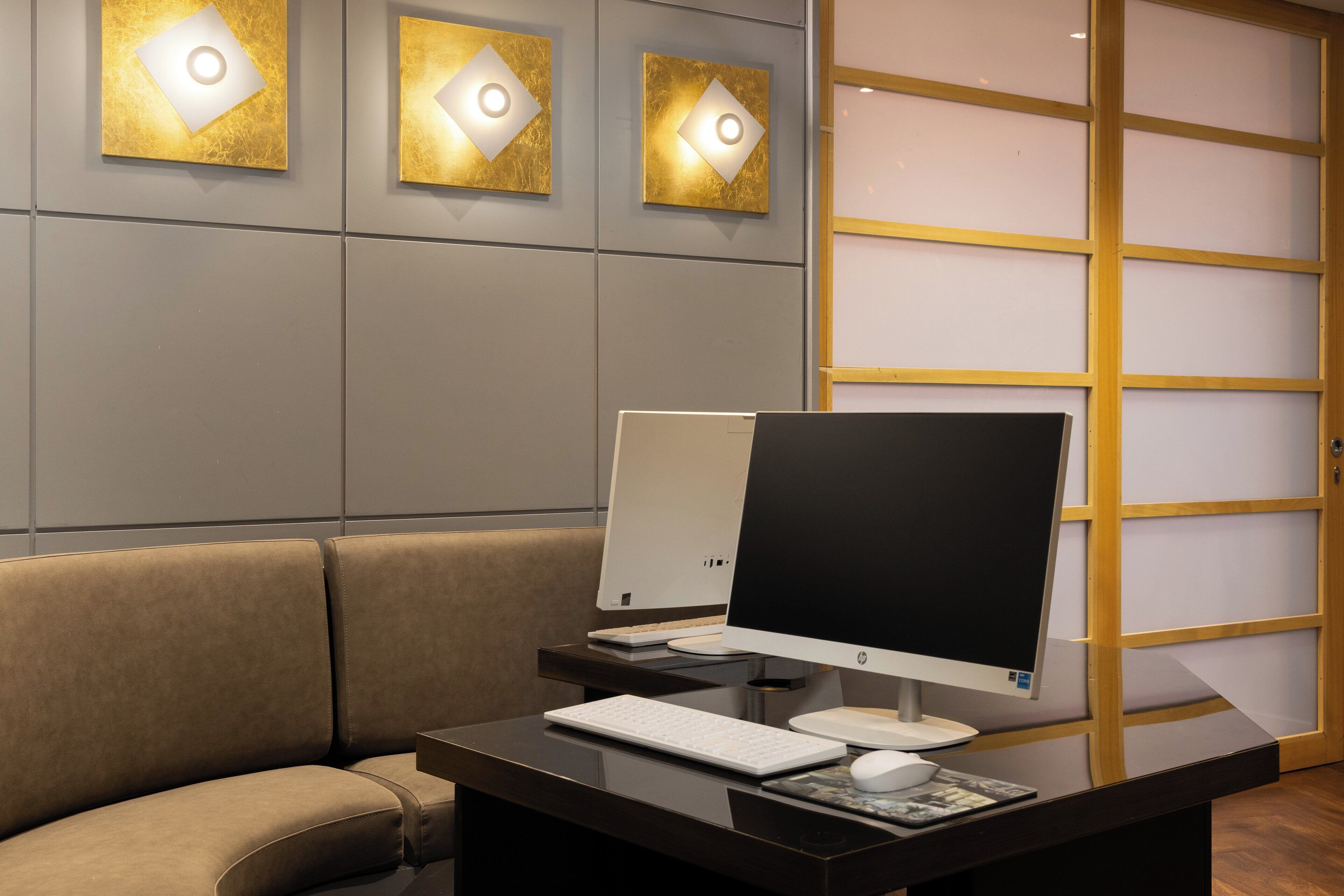 A modern office space with a desk, computer, keyboard, and mouse.