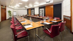A conference room with a long table, red chairs, and a projector screen. - Holiday Inn Milan - Garibaldi Station by IHG (Milan)