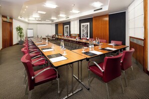 A conference room with a long table, red chairs, and a projector screen. - Holiday Inn Milan - Garibaldi Station by IHG (Milan)