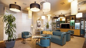 A modern living room with a sofa, chairs, a coffee table, and a potted plant. - Holiday Inn Milan - Garibaldi Station by IHG (Milan)