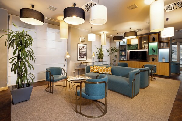 A modern living room with a sofa, chairs, a coffee table, and a potted plant. - Holiday Inn Milan - Garibaldi Station by IHG (Milan)