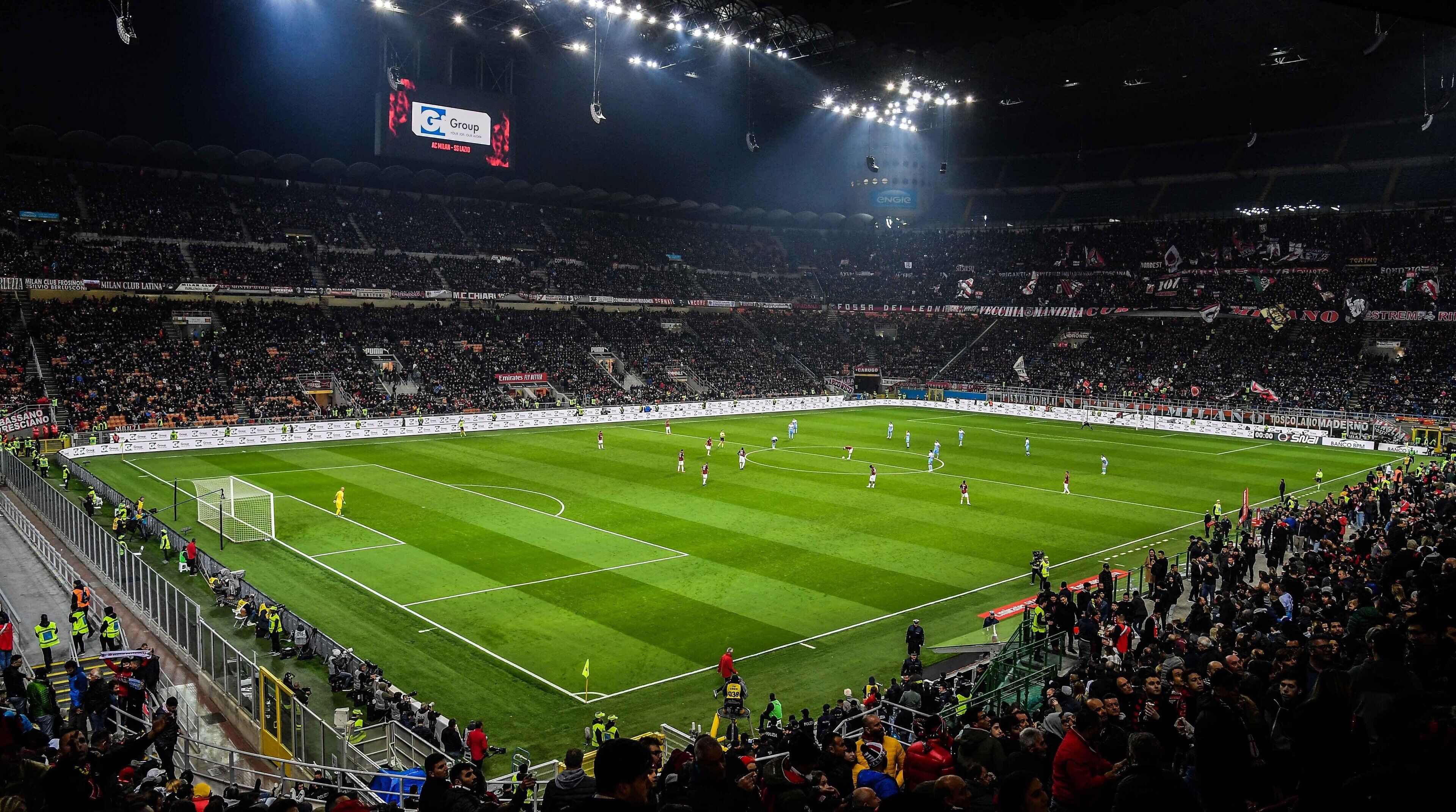 Un grand stade couvert doté d’un terrain de football, entouré d’une foule de spectateurs.