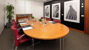 A conference room with a long table, red chairs, a potted plant, and framed pictures on the wall. - Holiday Inn Milan - Garibaldi Station by IHG (Milan)