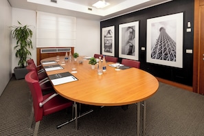 A conference room with a long table, red chairs, a potted plant, and framed pictures on the wall. - Holiday Inn Milan - Garibaldi Station by IHG (Milan)