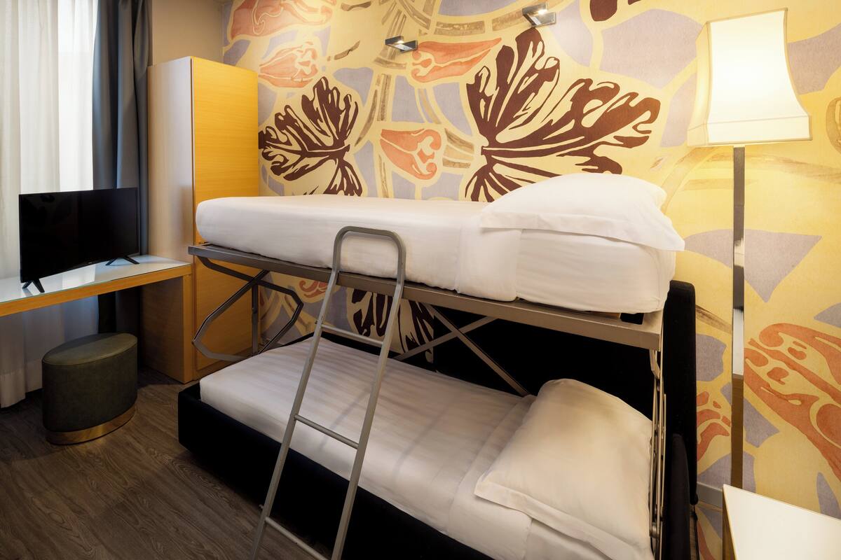 A bunk bed with a desk and a television in a hotel room.