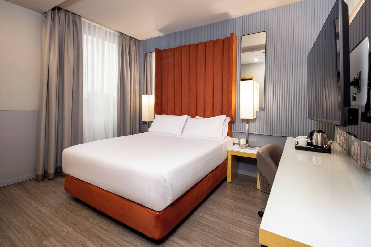 A hotel room with a large bed, a desk, and a chair.