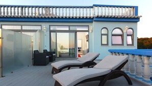 A modern building with a balcony featuring two lounge chairs and a glass door leading to an interior space. - Urban Hotel Santa Eulália (Albufeira)