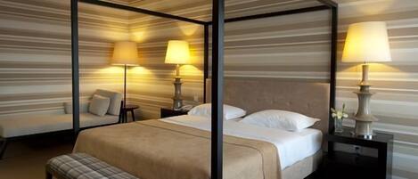 A four-poster bed with a bench, two bedside tables, and lamps.