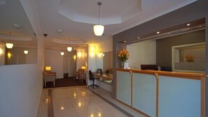 A hotel reception area with a modern design, including a reception desk, seating area, and a hallway leading to other rooms. - Hobart Waterfront Apartments (Hobart)
