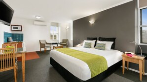 A modern hotel room with a large bed, a desk with a chair, a television, and a window. - Hobart Waterfront Apartments (Hobart)