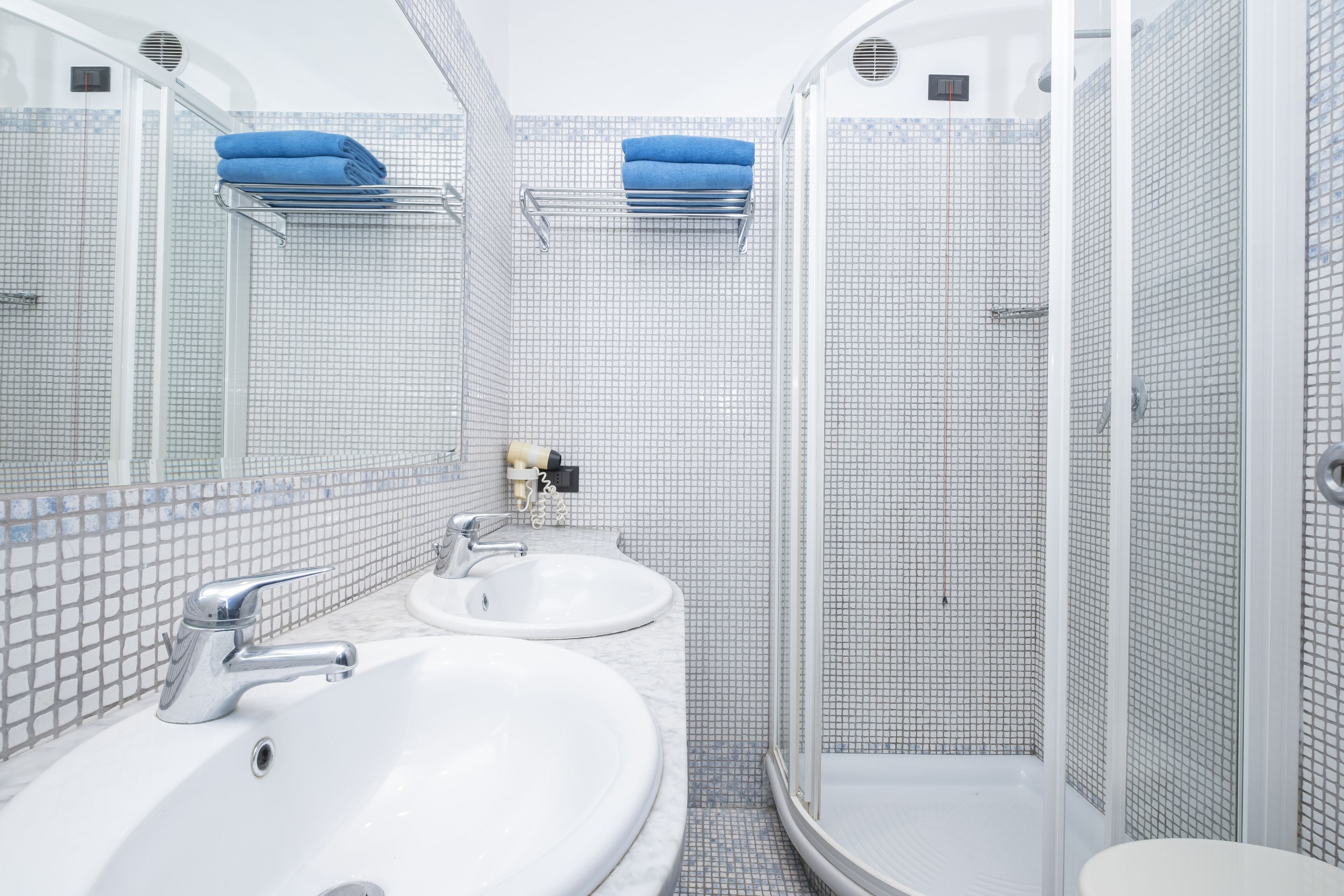 Un bagno moderno con due lavabi, uno specchio e una doccia.