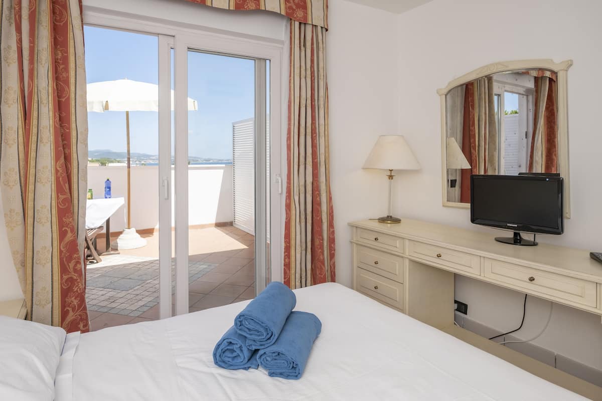 A hotel room with a bed, a TV, a desk, and a view of the outdoors.