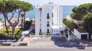 Ein weißes Gebäude mit einem Schild, das "HOTEL DEL SOLE" zeigt, umgeben von Bäumen und mit freiem Blick auf das Meer.