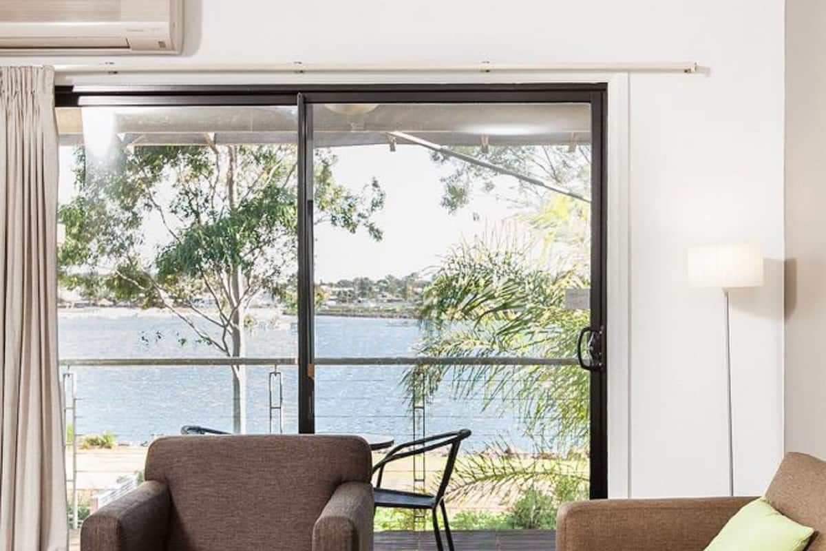Ein modernes Zimmer mit einer Couch, einem Sessel und einem Tisch. Es verfügt über eine große Schiebeglasdoor, die auf einen Balkon mit Meerblick führt.
