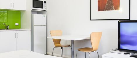 Una habitación de hotel moderna con una cama, un escritorio con computadora, un microondas y un refrigerador.