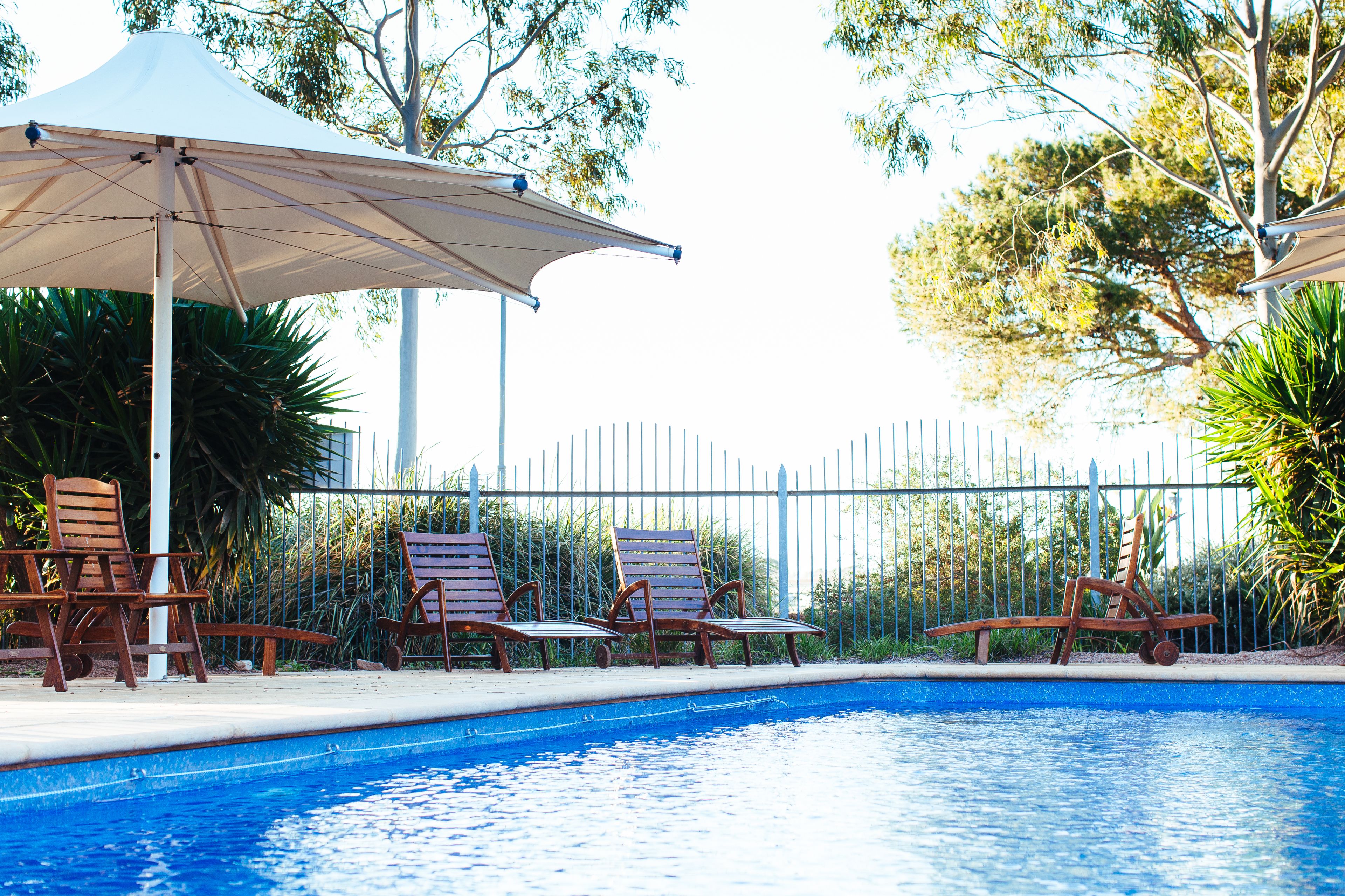 A swimming pool with lounge chairs and umbrellas.
