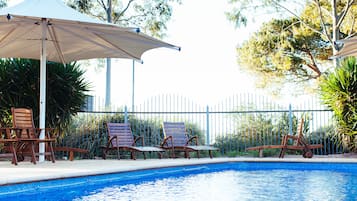 A swimming pool with lounge chairs and umbrellas.