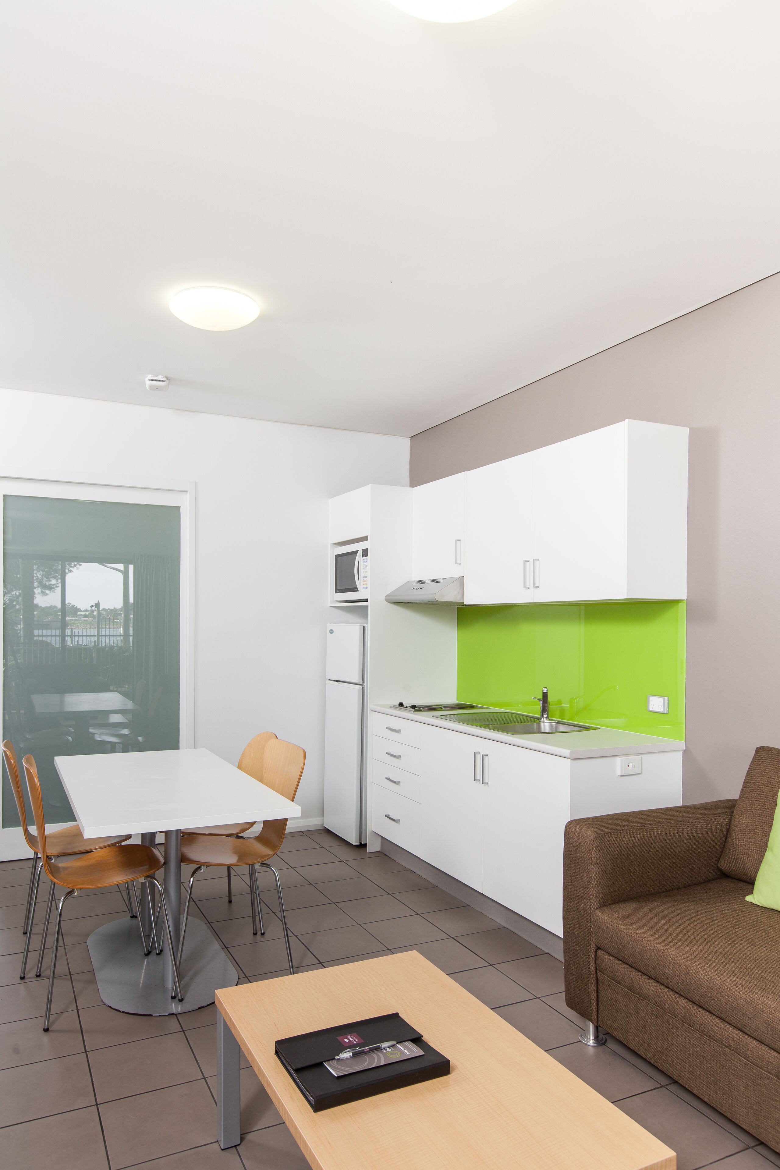 A modern kitchen with white cabinets, a green backsplash, and a dining area with a table and chairs.