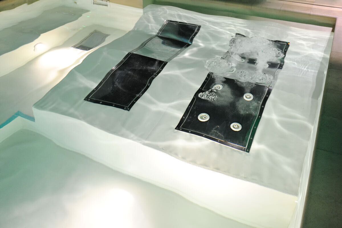 A spa area with a glass-enclosed hot tub, a black massage table, and a black massage chair.