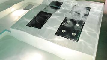 A spa area with a glass-enclosed hot tub, a black massage table, and a black massage chair.