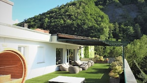 A modern house with a covered patio, outdoor seating, and a wooden barrel. - Hotel Santoli (Alto Reno Terme)