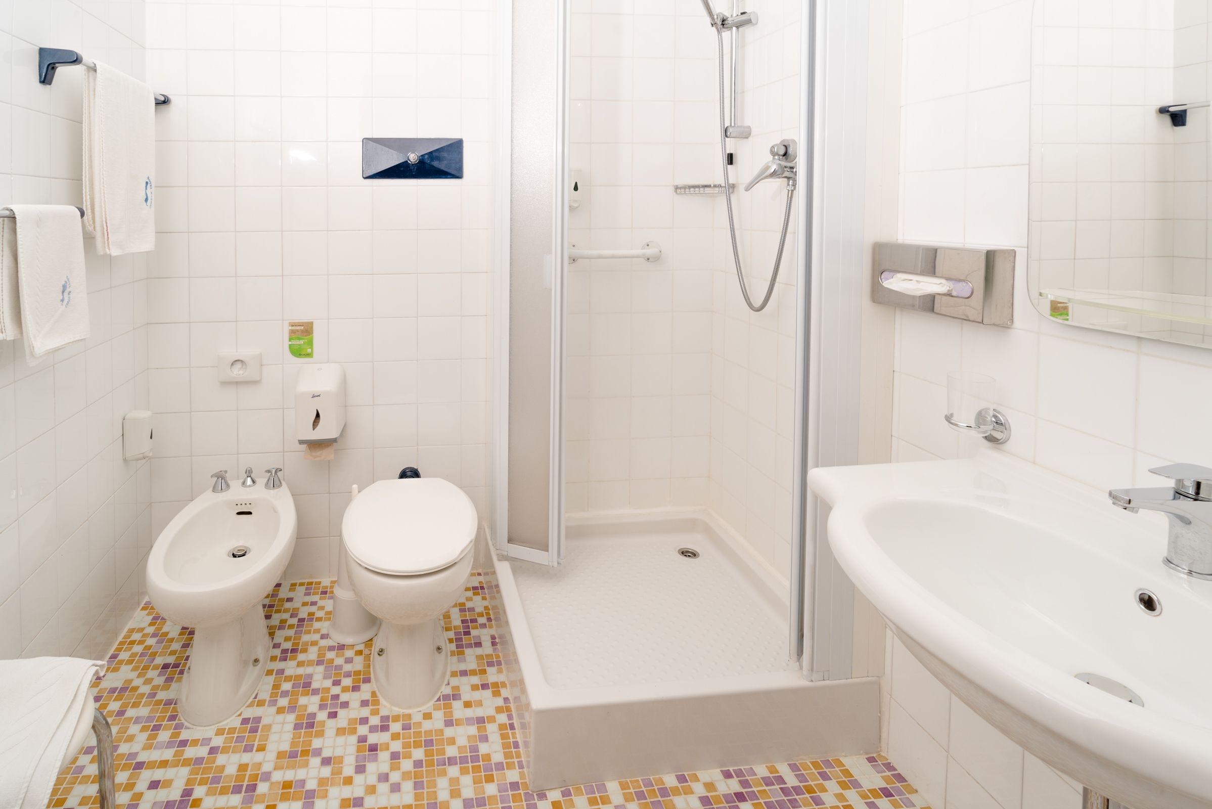 Een badkamer met twee toiletten, een bidet, een douche en een wastafel.