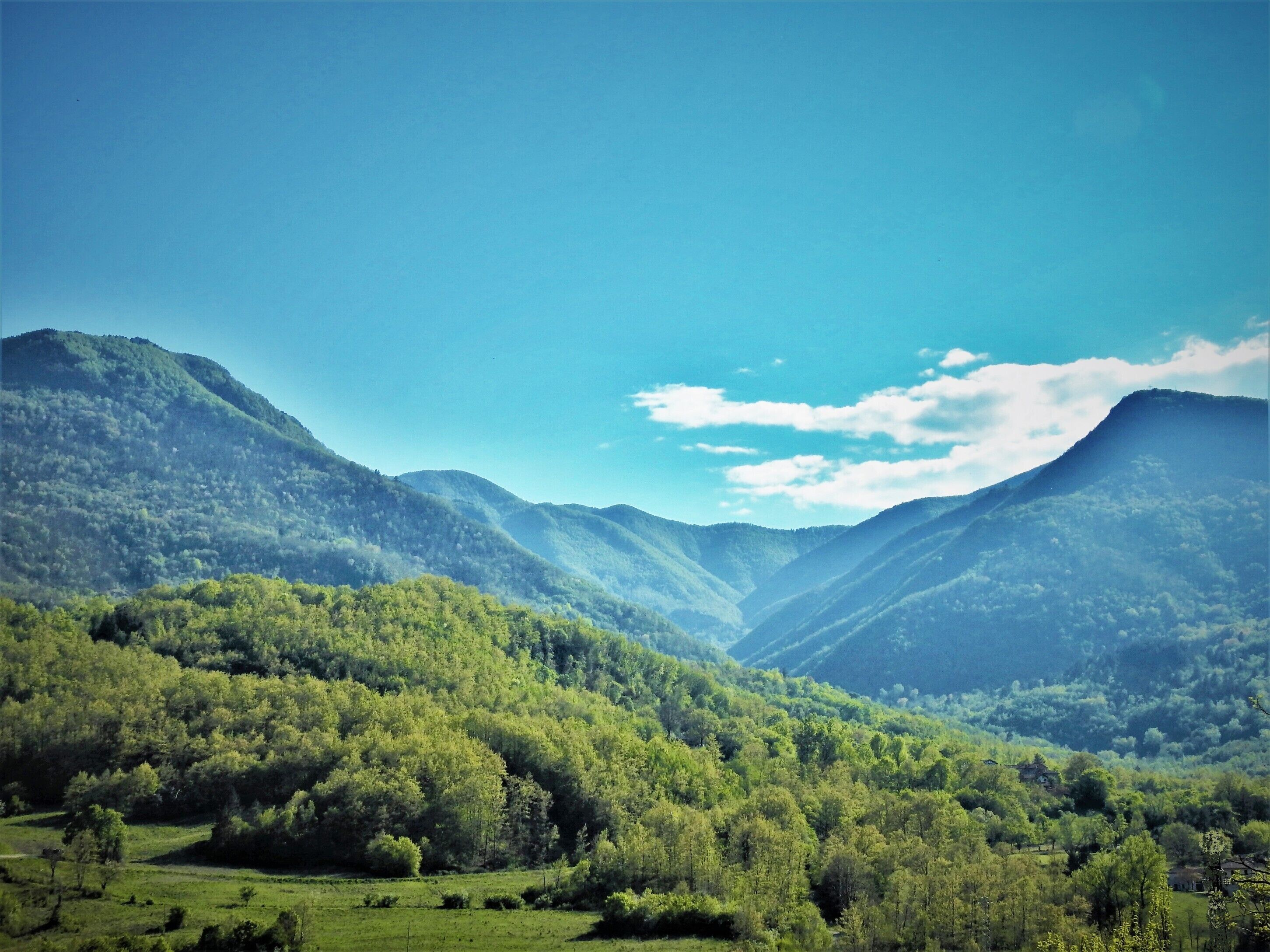 A mountainous landscape with lush green valleys and a clear sky.